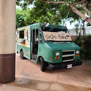 a green food truck parked on the side of the road