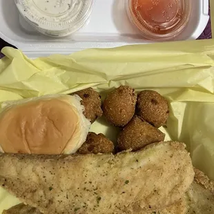 Tilapia plate with hush puppies, roll, hot sauce and tater sauce