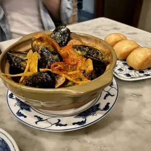 a bowl of mussels and bread on a table