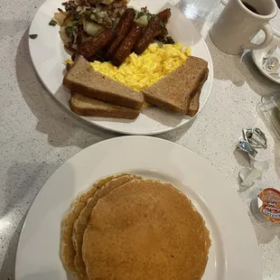 a plate of pancakes, eggs, sausages, and hash browns