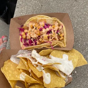 a hand holding a tortilla and chips