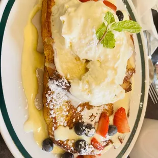 a plate of french toast with whipped cream and berries