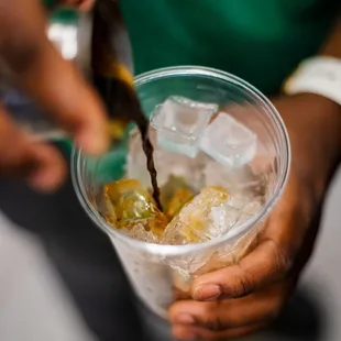 a person pouring a drink into a cup