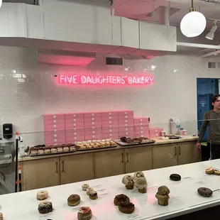 a woman standing in front of a counter with pastries on it