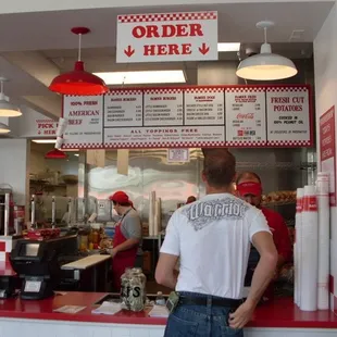 a man standing at the counter of a fast food restaurant