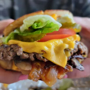 a hand holding a cheeseburger