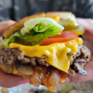 a hand holding a cheeseburger