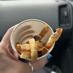 a person holding a bowl of fries