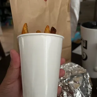 a hand holding a cup of fries
