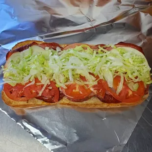 a hot dog with tomatoes and lettuce