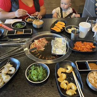 a woman and a baby sitting at a table full of food