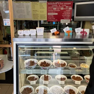 a woman standing in front of a display case filled with food
