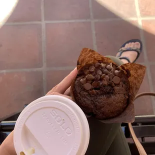 a person holding a cup of coffee and a muffin