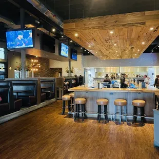 a bar with stools and televisions