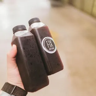 a hand holding two bottles of coffee