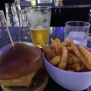 Burger, fries, beer, and an empty glass.