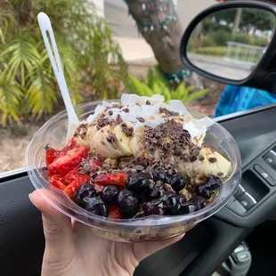 a hand holding a bowl of fruit