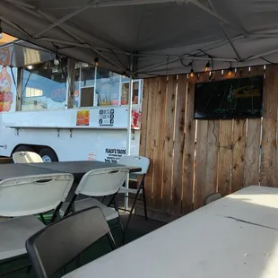 Table set up with a TV, and the food truck in the background.