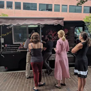 a group of people standing in front of a food truck
