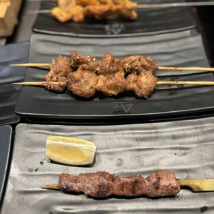 skewers of meat on skewers with lemon wedges