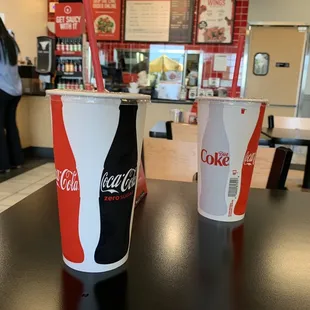 two coke cola cups on a table