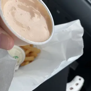 a hand holding a cup of sauce