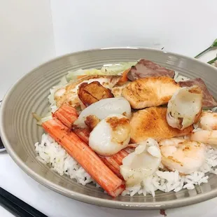 a bowl of rice with shrimp, carrots, and scallops