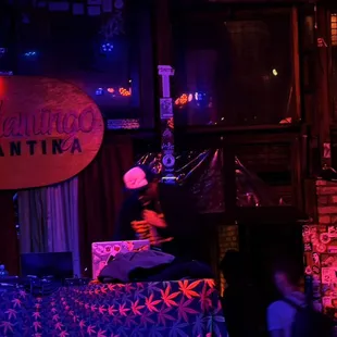 a woman sitting at a table in front of a neon sign