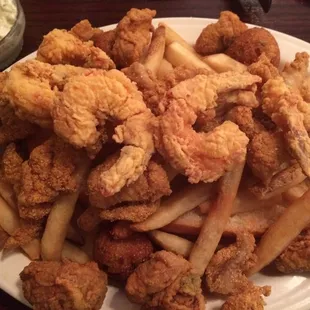 The seafood platter buried underneath is a long piece of toasted French bread or have a po boy bun, with tartar sauce and red sauce.