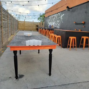 a patio with tables and orange stools