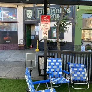 two lawn chairs and a no parking sign