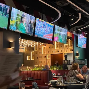 people sitting at tables and watching tvs