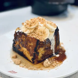 &apos;The Cube&quot; brioche French toast filled with chocolate-hazelnut ganache, fresh banana slices, hazelnut crumble, and vanilla-infused syrup
