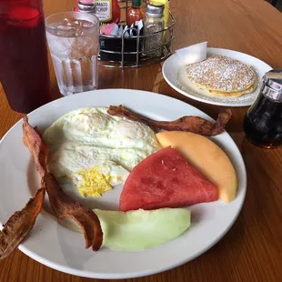 Over easy eggs, bacon, flapjacks and side of fruit