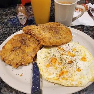 a plate of fried eggs and a cup of orange juice