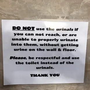 a sign on a bathroom wall stating to not use the urinals if you can not reach or are unable to