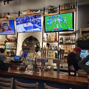 people sitting at a bar watching televisions
