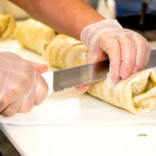 a person cutting a pastry with a knife