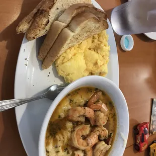 a bowl of shrimp and grits with bread