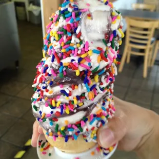 a hand holding a cone of ice cream and sprinkles