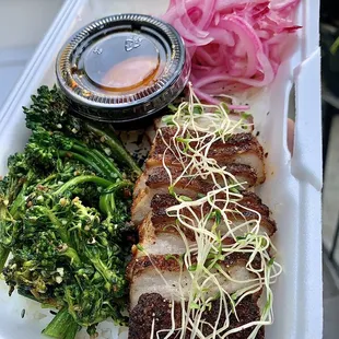 a styrofoam container with meat and vegetables