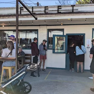 a group of people standing outside of a coffee shop