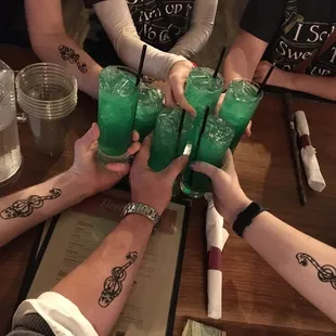 a group of people holding green cocktails