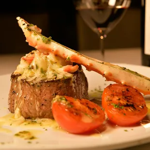 a piece of steak with crab legs and tomatoes