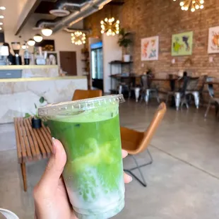 a hand holding a green drink