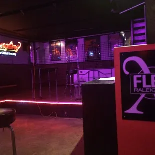 a bar with a neon sign and stools