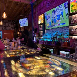 High tops that look like the insides of pinballs machines, the bar and a big screen TV.