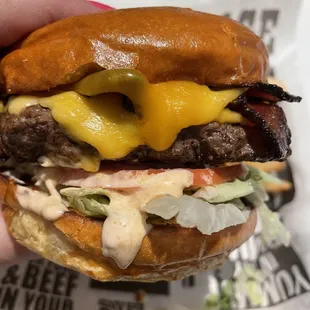 a hand holding a hamburger with cheese and lettuce