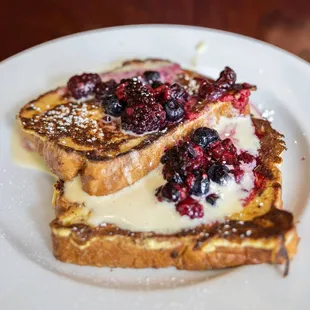 a plate of french toast with berries and cream