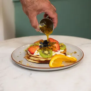a person pouring syrup onto a plate of food